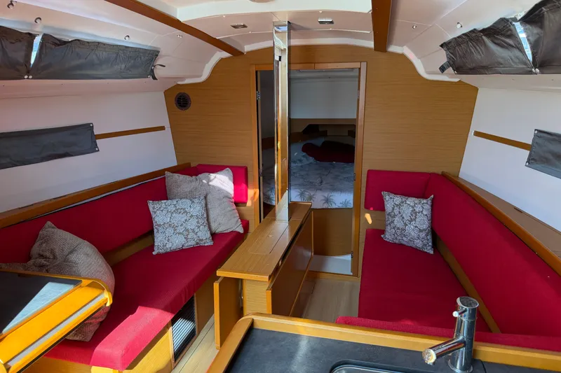 Slide: The Image of Interior of 2015 Jeanneau Sun Odyssey 349 sailboat with red seating and wooden accents. - 19