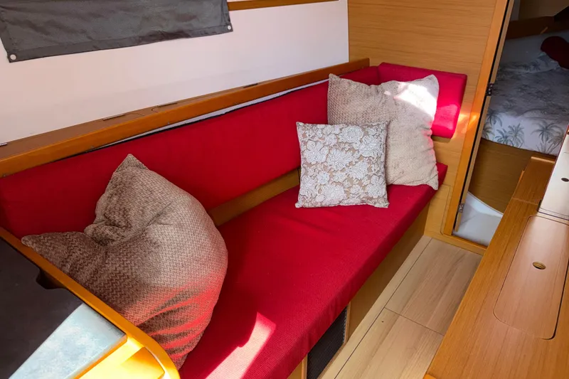 Slide: The Image of Red cushioned seating area with pillows inside a 2015 Jeanneau Sun Odyssey 349 yacht. - 23