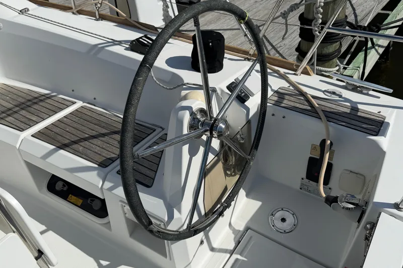 Slide: The Image of Steering wheel of a 2015 Jeanneau Sun Odyssey 349 sailboat, featuring teak seating and control panel. - 6