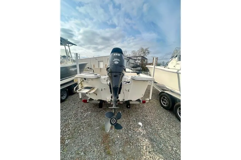 Slide: The Image of 2015 Carolina Skiff 198 DLV boat with outboard motor, parked on gravel. - 3
