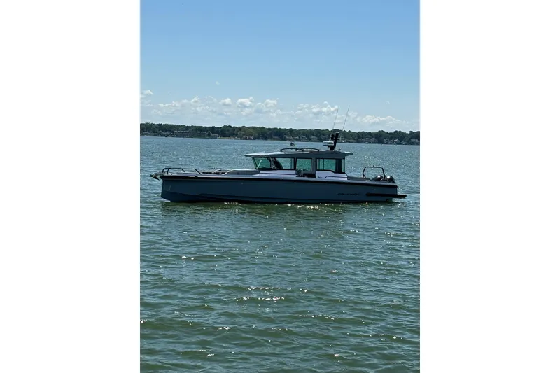 The Image of 2024 Axopar 37 XC Cross Cabin boat on calm water under clear sky. - 0