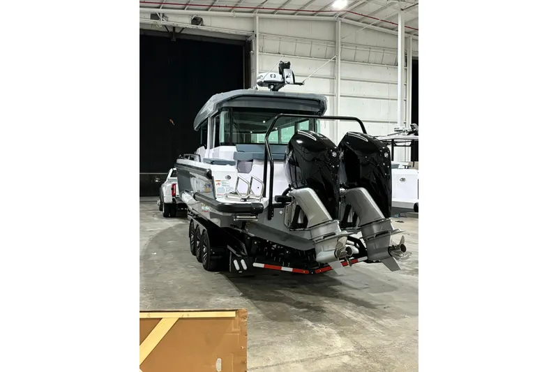 Slide: The Image of 2024 Axopar 37 XC Cross Cabin boat with dual engines in a warehouse setting. - 5