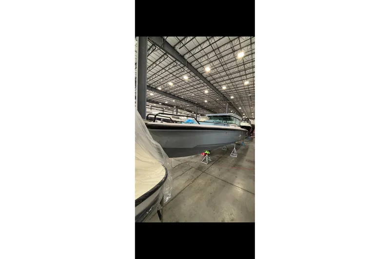 Slide: The Image of 2024 Axopar 37 XC Cross Cabin boat in a spacious indoor showroom. - 9