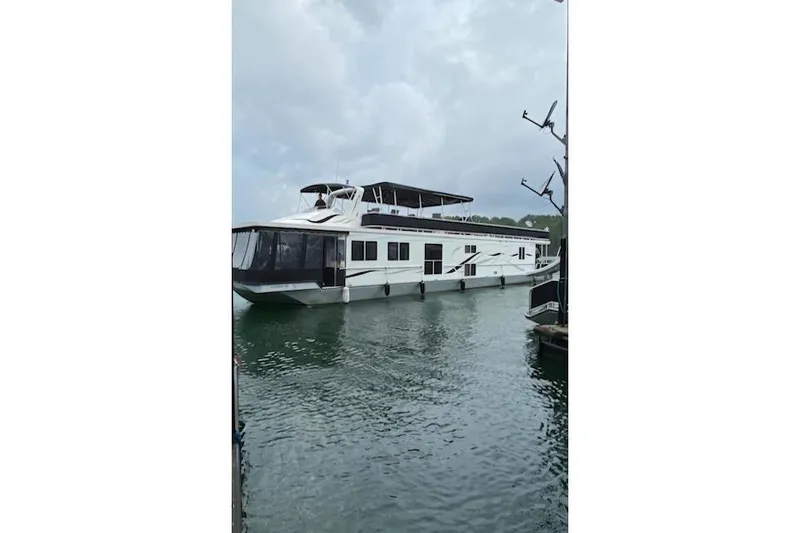 The Image of 2005 Starlite 16x82 houseboat on calm water under cloudy sky. - 0