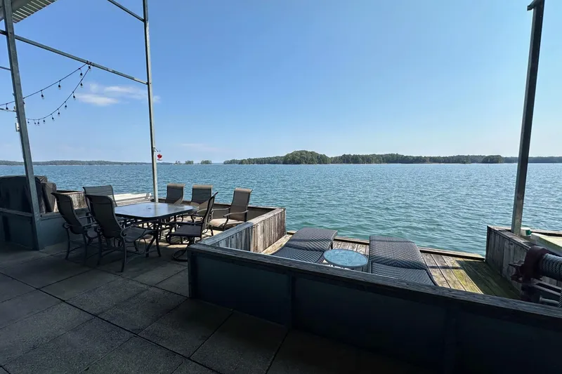 Slide: The Image of Lakeside deck with seating, overlooking serene water and distant islands, under a clear blue sky. - 16