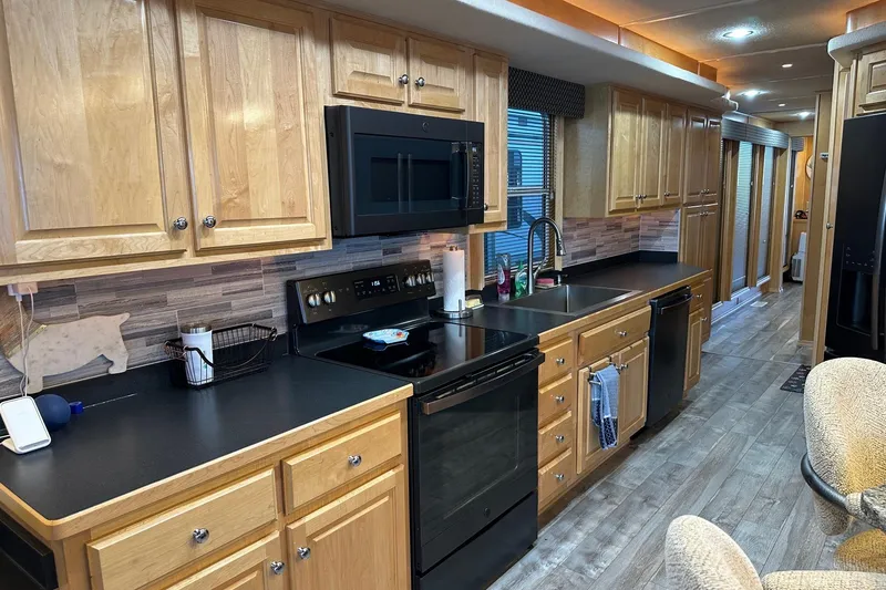 Slide: The Image of Modern kitchen in a 2005 Starlite 16x82 houseboat with wooden cabinets and black appliances. - 5