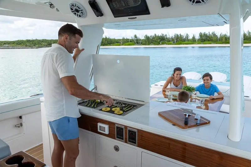 Slide: The Image of Manufacturer Provided Image: Man grilling on 2026 Regal 43 SAV yacht with family dining nearby. - 7