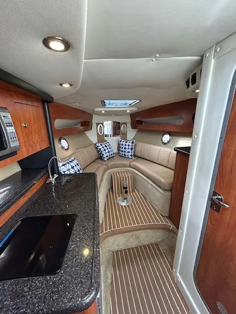 Slide: The Image of Interior of 2013 Rinker 290 Express Cruiser with modern kitchen and cozy seating area. - 13