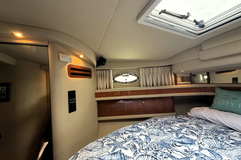 Slide: The Image of Interior cabin of 2000 Sea Ray 450 Express Bridge yacht, featuring cozy bedding and porthole window. - 24