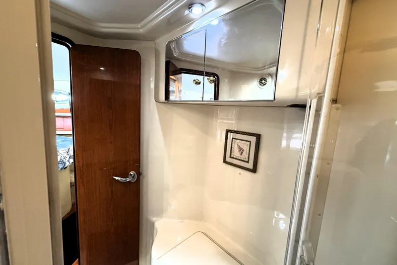 Slide: The Image of Interior of 2000 Sea Ray 450 Express Bridge, featuring a compact bathroom with wood door and mirror. - 33