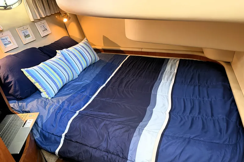 Slide: The Image of Cozy bedroom in 2000 Sea Ray 450 Express Bridge with blue bedding and striped pillows. - 46