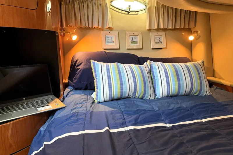 Slide: The Image of Cozy cabin interior of 2000 Sea Ray 450 Express Bridge with striped bedding and laptop. - 47