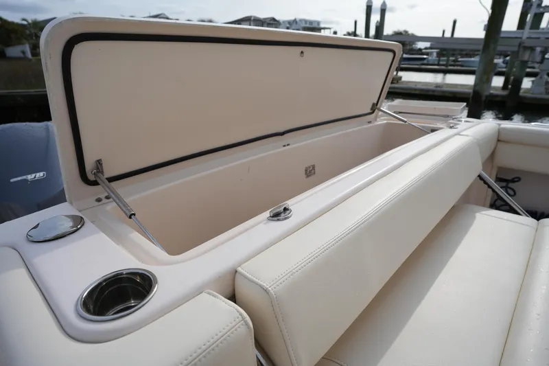 Slide: The Image of Open storage compartment on 2009 Grady-White Express 330 boat, featuring cushioned seating and cup holder. - 17