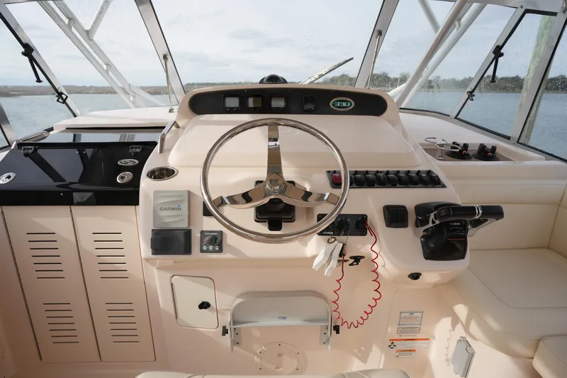 Slide: The Image of 2009 Grady-White Express 330 helm with steering wheel and navigation controls. - 33