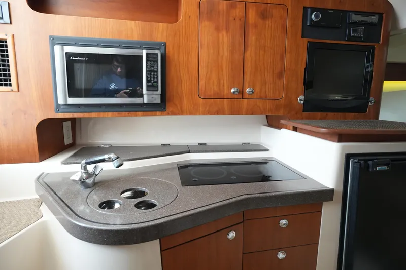 Slide: The Image of 2009 Grady-White Express 330 boat kitchen with microwave, stove, and wooden cabinetry. - 46
