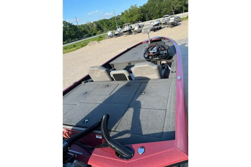 Slide: The Image of 2024 Avid 20 XB boat interior with steering wheel and seating, parked outdoors. - 21