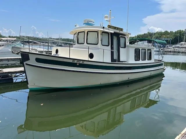 The Image of 2001 Nordic Tug 32 boat docked in a marina, reflecting on calm water. - 0