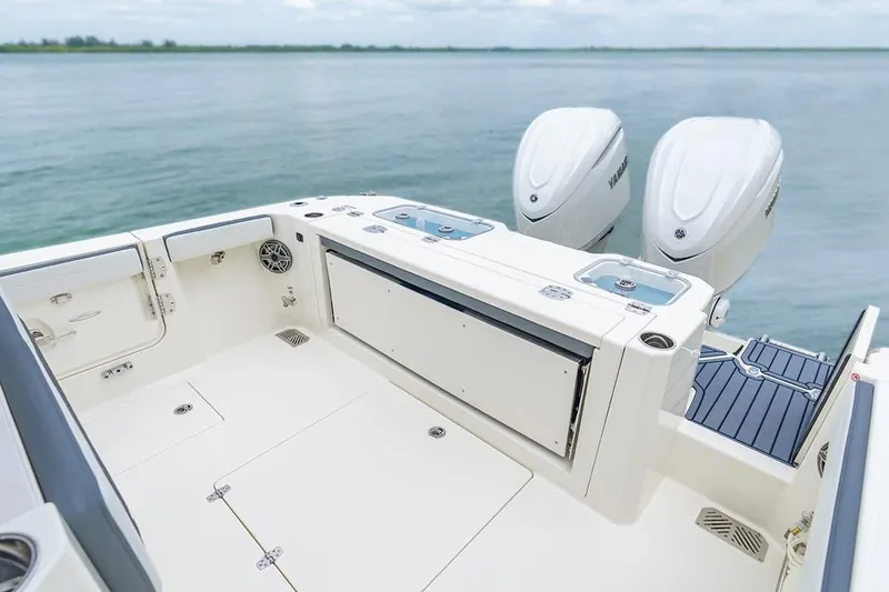 Slide: The Image of 2026 Cobia 305 Center Console boat with dual engines on calm water. - 2