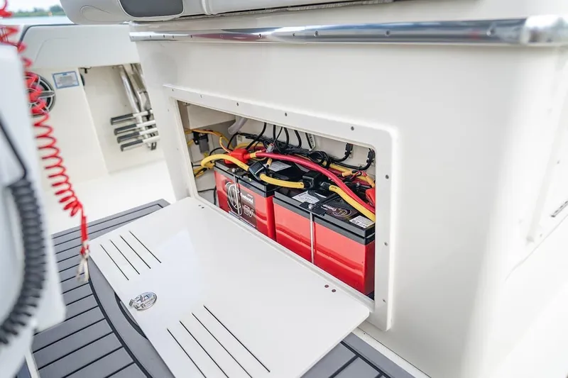 Slide: The Image of 2026 Cobia 305 Center Console boat battery compartment with wiring and red batteries. - 22