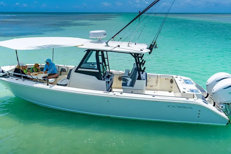 Slide: The Image of 2026 Cobia 305 Center Console boat on turquoise water, with people enjoying a meal. - 39