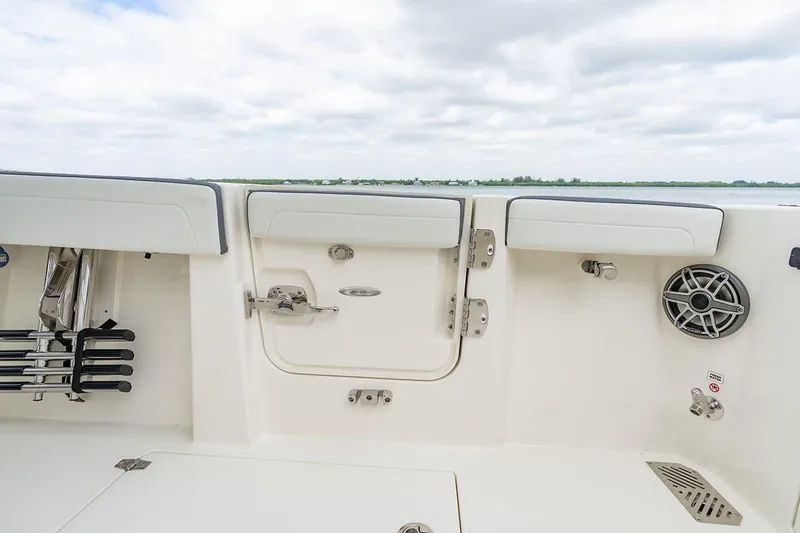 Slide: The Image of 2026 Cobia 305 Center Console boat interior with seating and speaker, under cloudy sky. - 7