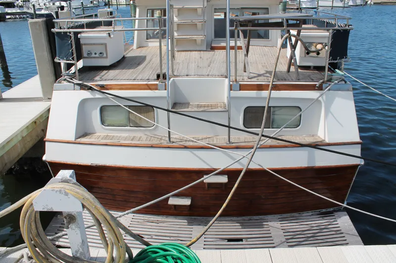 Slide: The Image of 1987 Grand Banks 42 Motoryacht docked at marina, showcasing wooden deck and nautical equipment. - 2