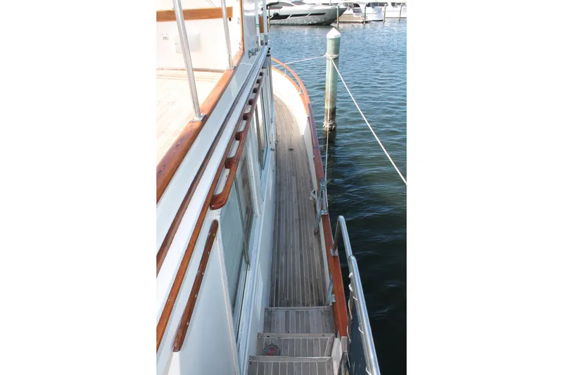 Slide: The Image of Side deck view of 1987 Grand Banks 42 Motoryacht, featuring wooden railings and docked at marina. - 4