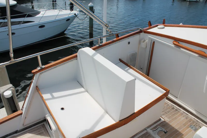 Slide: The Image of 1987 Grand Banks 42 Motoryacht deck with white seating and wooden railings at marina. - 9
