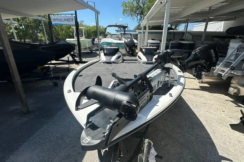 Slide: The Image of 2026 Vexus AVX1880 boat with trolling motor, parked under a canopy at a dealership. - 3