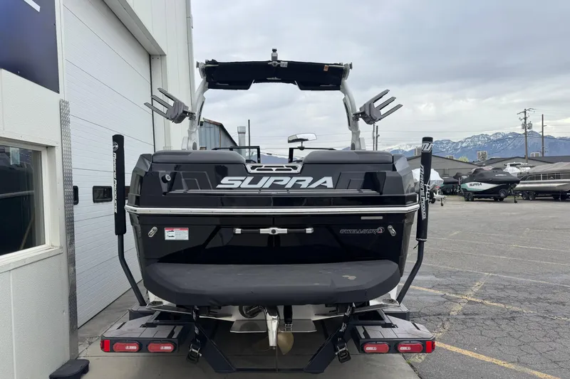 Slide: The Image of 2024 Supra SA 450 boat rear view at a marina with mountains in background. - 4