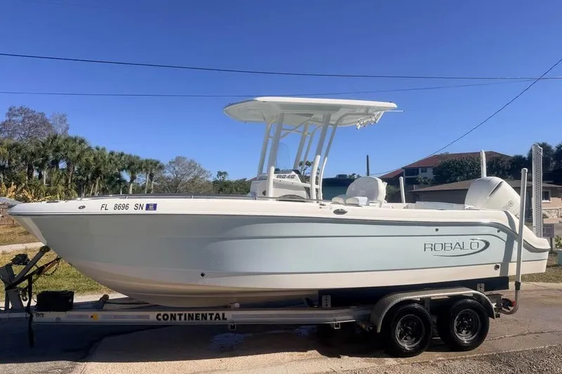 The Image of 2020 Robalo R242 Explorer boat on trailer under clear blue sky. - 1