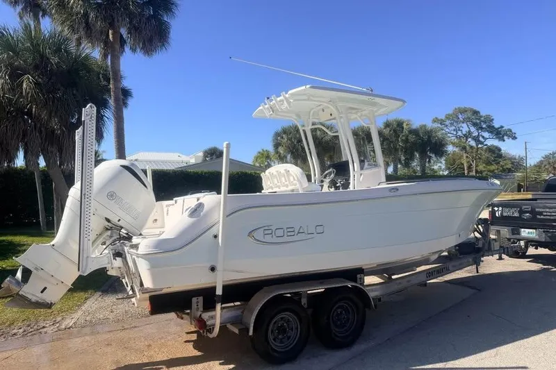 Slide: The Image of 2020 Robalo R242 Explorer boat on trailer, parked outdoors under clear sky. - 4