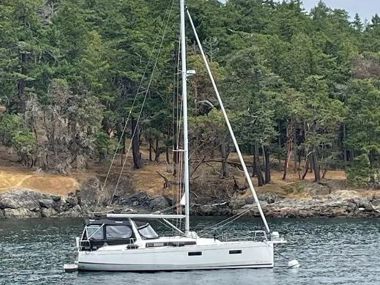Slide: The Image of 2022 Beneteau Oceanis 38.1 sailboat on calm water, forested shoreline in background. - 33