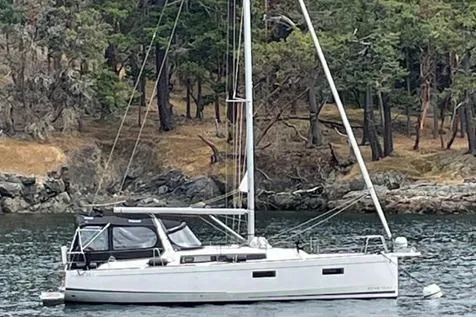 Slide: The Image of 2022 Beneteau Oceanis 38.1 sailboat on calm water, forested shoreline in background. - 34