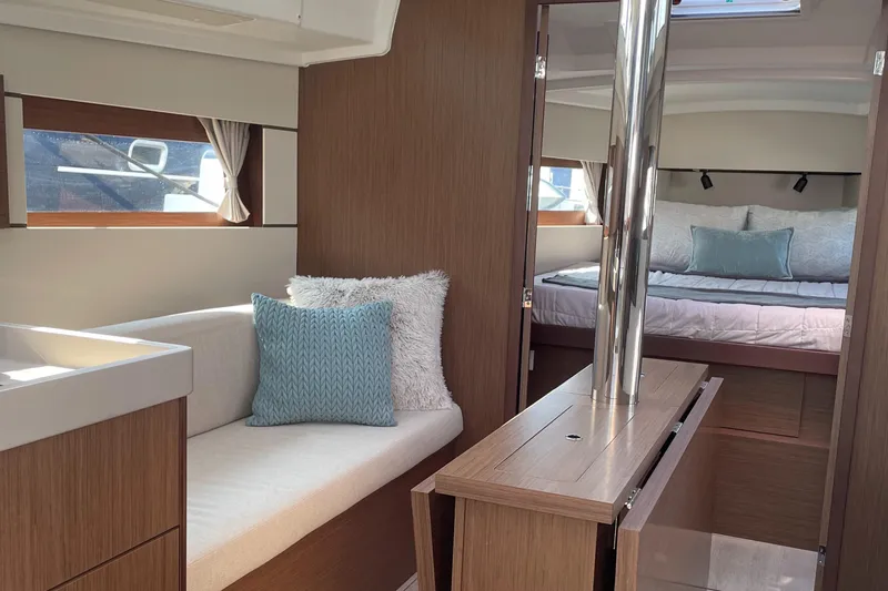 Slide: The Image of Interior of 2022 Beneteau Oceanis 38.1 yacht, featuring cozy seating and elegant wood finishes. - 9