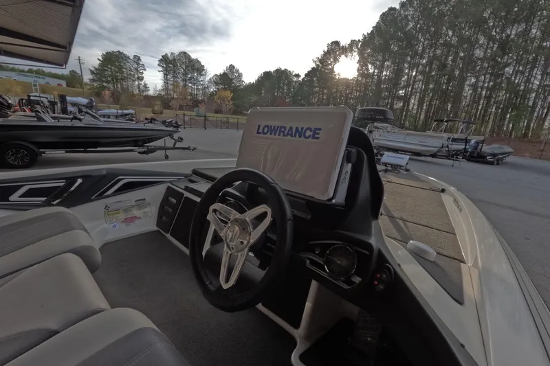 Slide: The Image of 2015 Skeeter FX21 boat interior with Lowrance navigation system, parked outdoors near trees. - 9