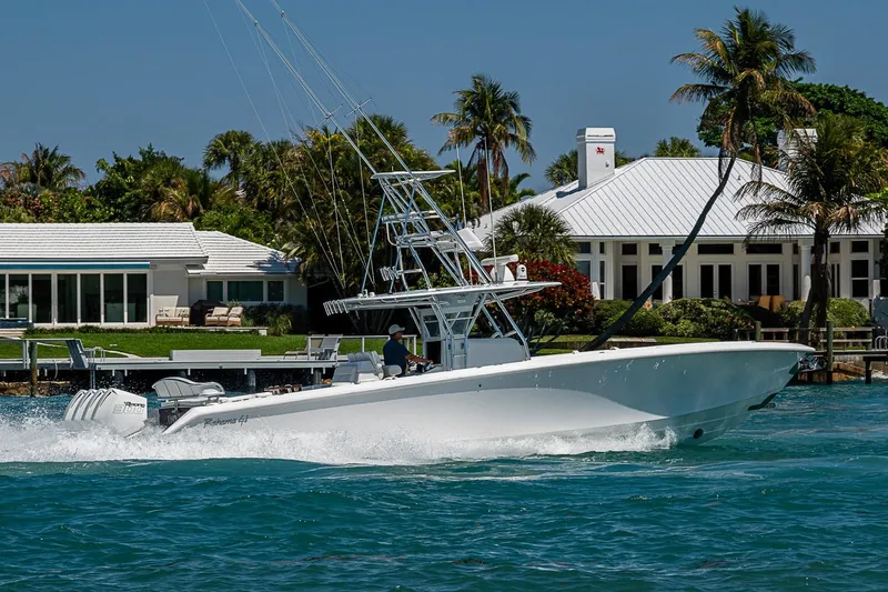 Slide: The Image of 2017 Bahama 41 boat cruising near waterfront property with palm trees and clear blue sky. - 10