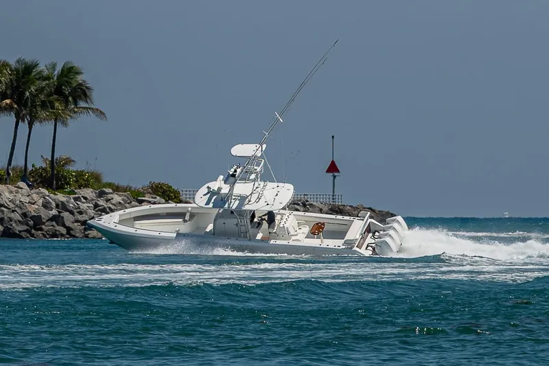 Slide: The Image of 2017 Bahama 41 boat cruising near rocky shoreline with palm trees and clear blue water. - 13