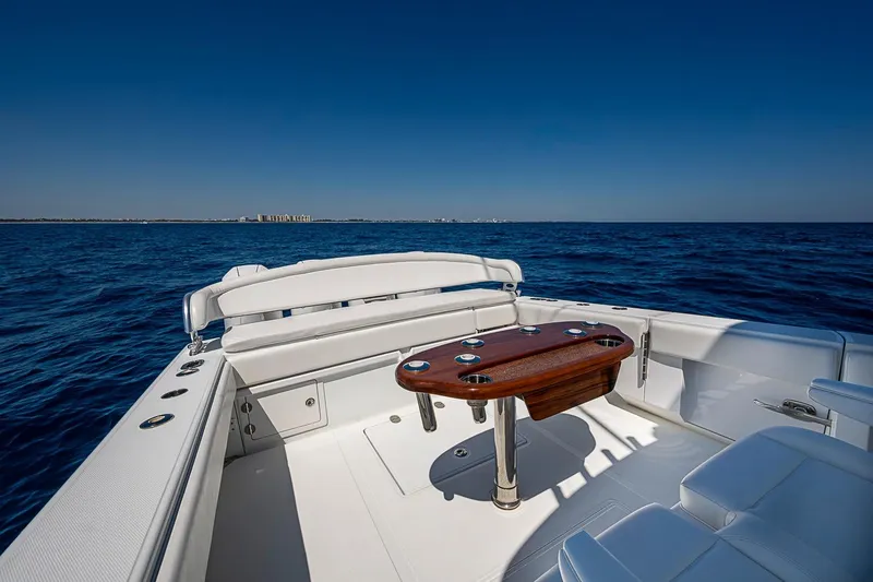 Slide: The Image of 2017 Bahama 41 boat interior with wooden table, surrounded by ocean under clear blue sky. - 15