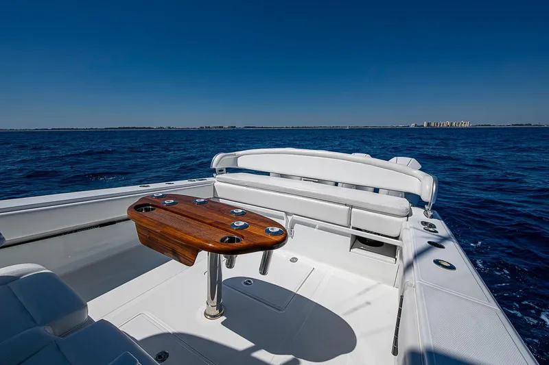 Slide: The Image of 2017 Bahama 41 boat with wooden table, white seating, and ocean view. - 17