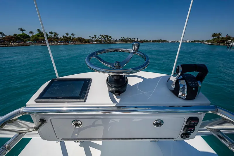 Slide: The Image of Helm of 2017 Bahama 41 boat with steering wheel and controls, overlooking blue water. - 44