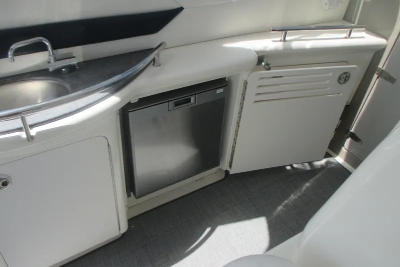 Slide: The Image of 2005 Sea Ray 390 Sundancer yacht kitchenette with sink, fridge, and storage cabinets. - 15