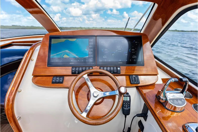 Slide: The Image of Helm of 2008 Hinckley Talaria 38R with wooden dashboard and modern navigation screens. - 15