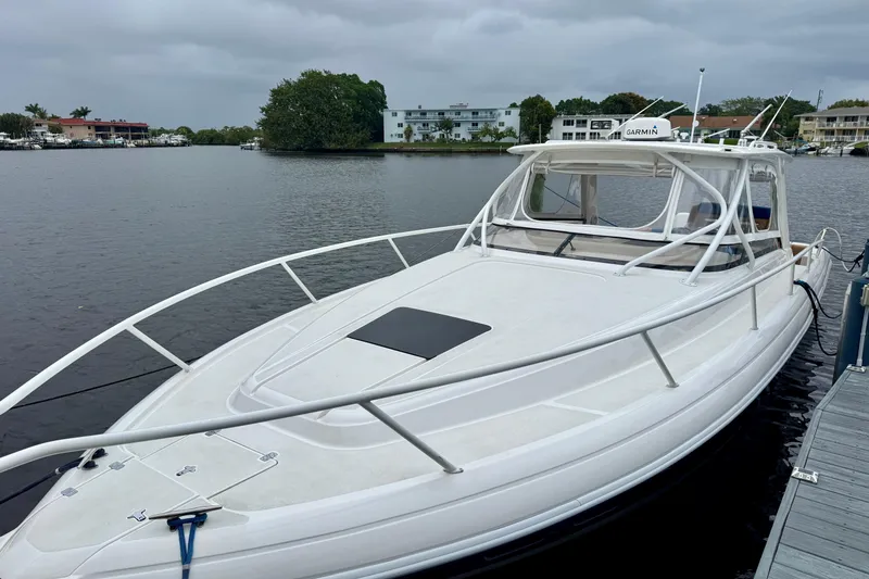 Slide: The Image of 2012 Intrepid 390 Sport Yacht docked on a calm waterfront under cloudy skies. - 2
