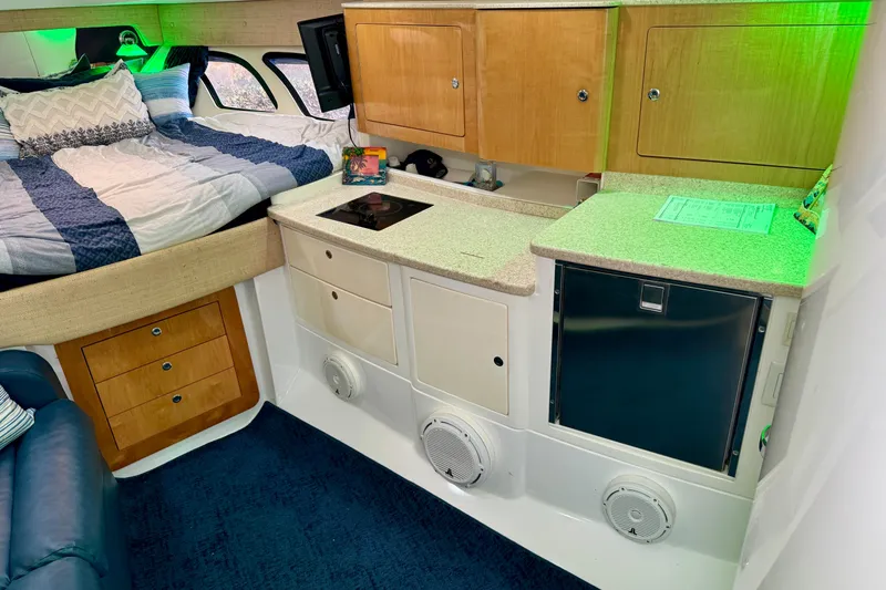 Slide: The Image of Interior of 2012 Intrepid 390 Sport Yacht with bed, kitchenette, and storage cabinets. - 23