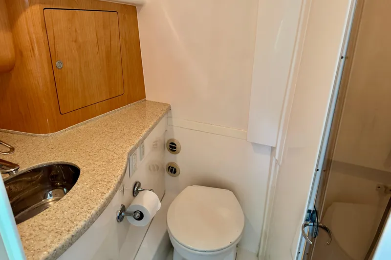 Slide: The Image of 2012 Intrepid 390 Sport Yacht bathroom with sink, toilet, and wooden cabinetry. - 27