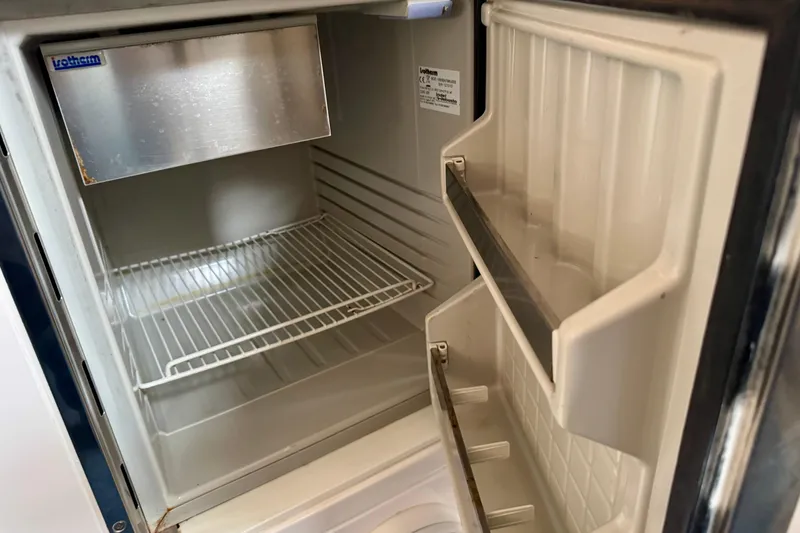 Slide: The Image of Empty refrigerator inside a 2012 Intrepid 390 Sport Yacht, featuring wire shelf and door storage. - 34