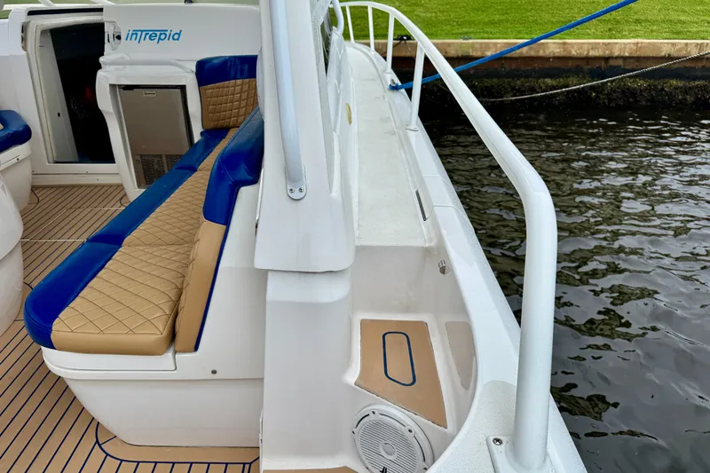 Slide: The Image of 2012 Intrepid 390 Sport Yacht interior with blue and tan seating, docked by water. - 41