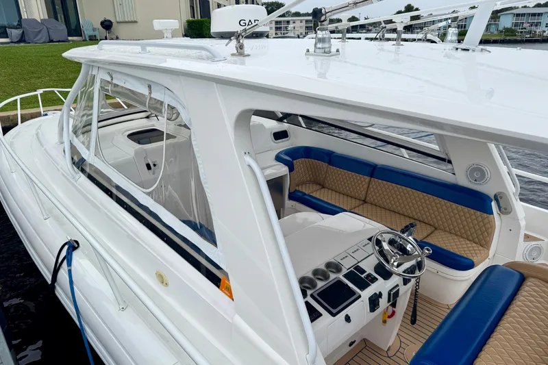 Slide: The Image of 2012 Intrepid 390 Sport Yacht with blue and tan seating, docked near waterfront homes. - 47