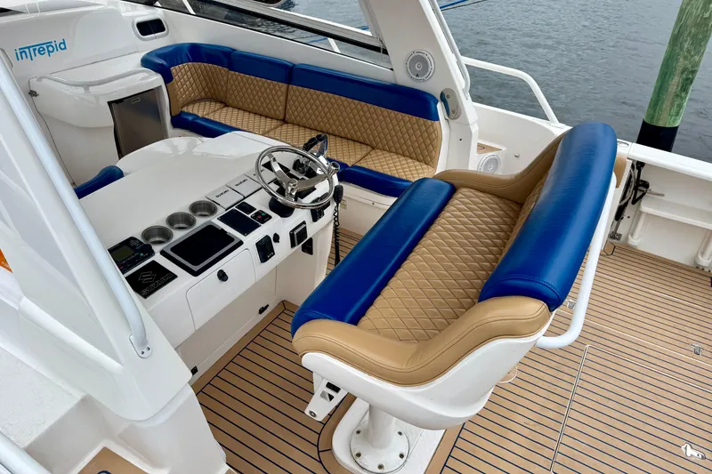 Slide: The Image of Interior of 2012 Intrepid 390 Sport Yacht with blue and tan seating, steering console. - 5